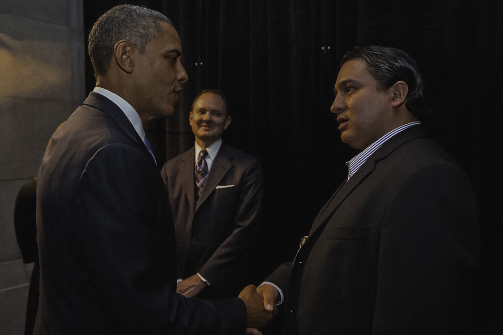 An image of two men in suits shaking hands as they greet each other.
